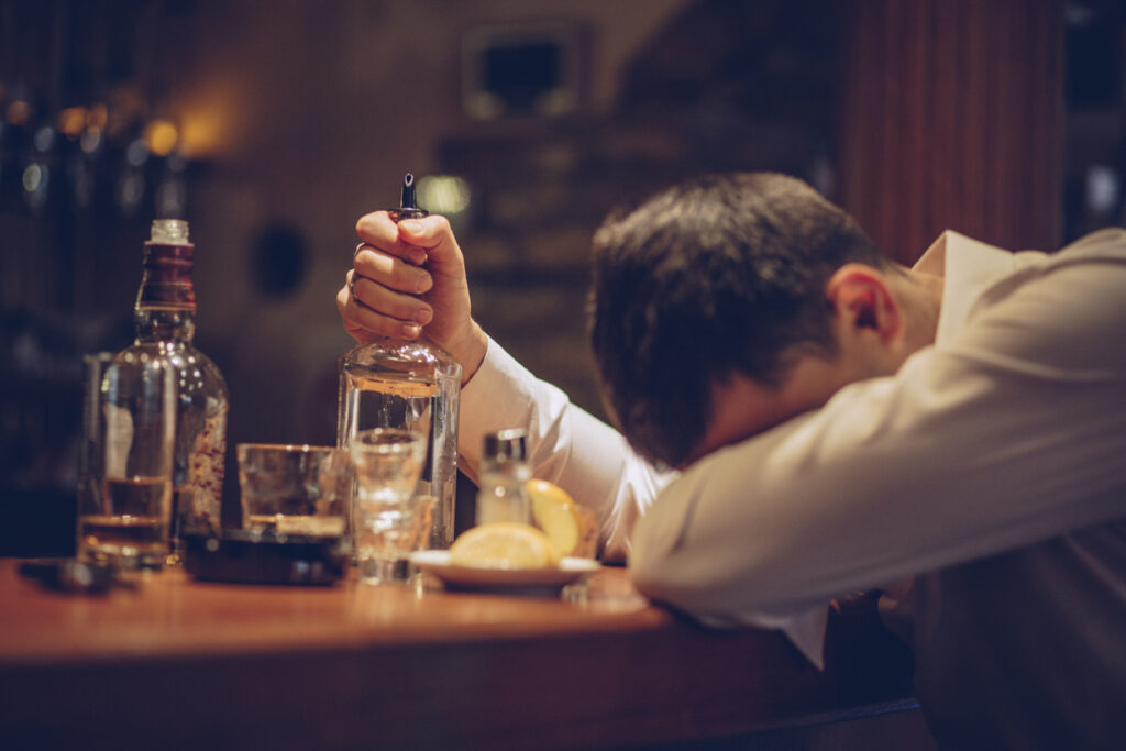man slumped at a bar holding a bottle, depicting binge drinking and alcohol blackout in Spokane, Washington State (WA) and Spokane Valley