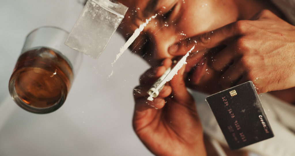 Man using cocaine with a rolled bill and drink nearby showing the need for cocaine detox in Spokane WA