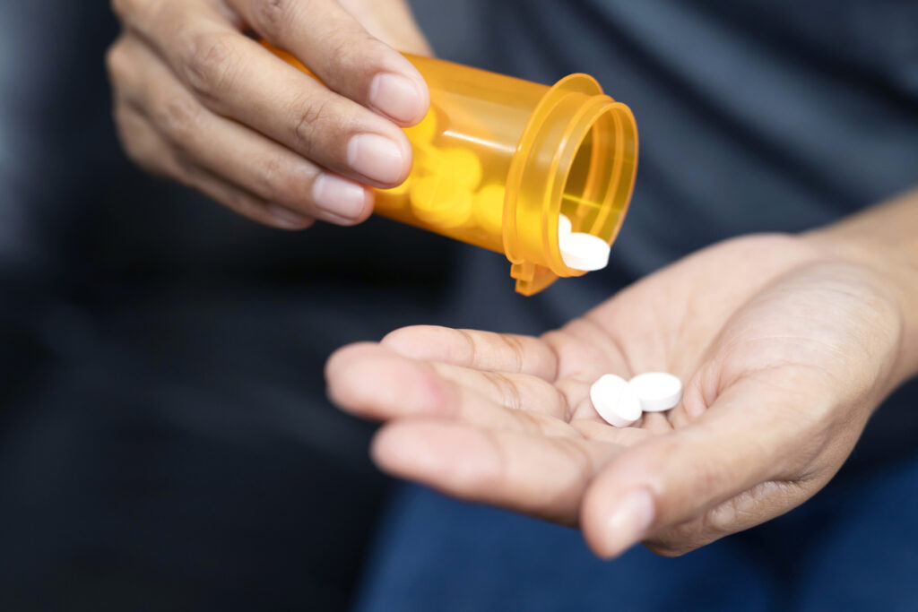 hand pouring prescription pills from an orange bottle, representing percocet drug addiction risk and help in Spokane Valley, WA and greater Washington State