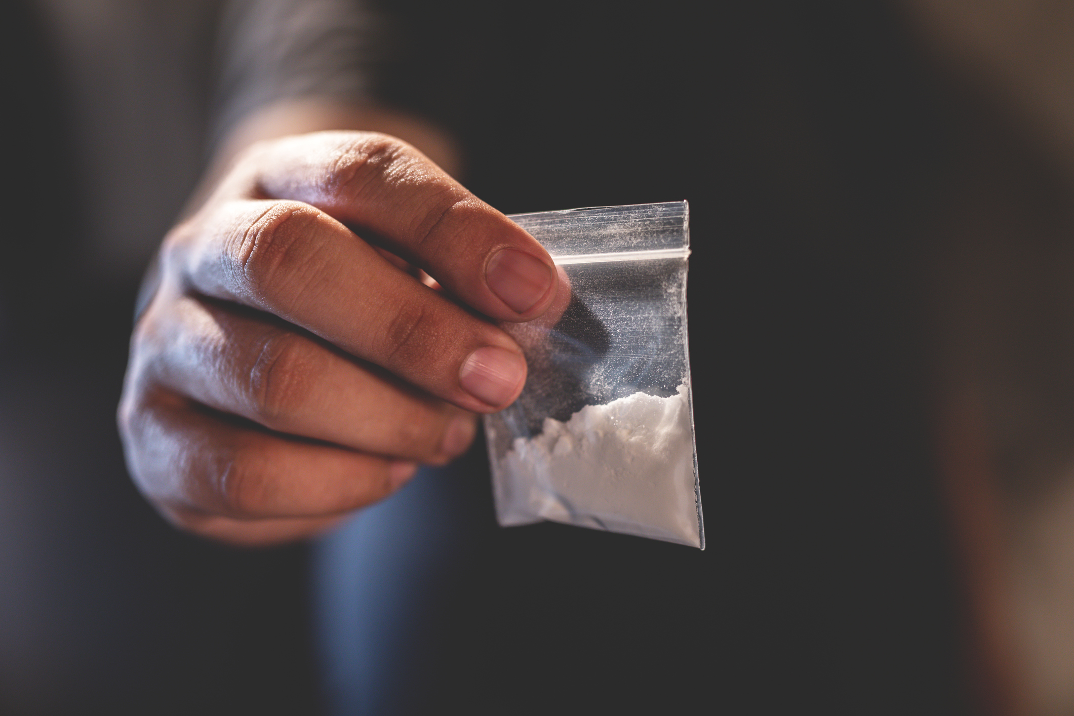 Hand holding a small plastic bag of white powder symbolizing amphetamine addiction issues in Spokane Valley, Washington State.