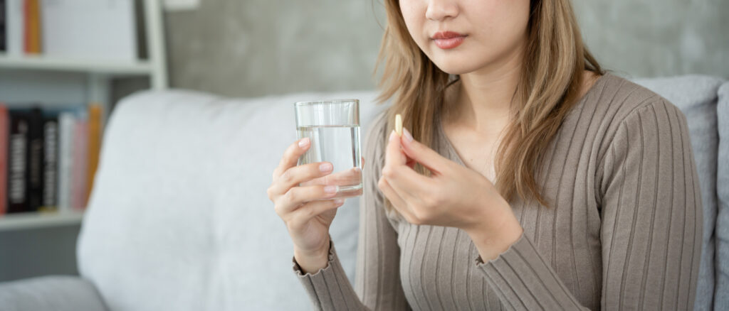 Woman holding a pill and a glass of water, highlighting awareness of drug overdose symptoms in Spokane, Spokane Valley, and Washington State.