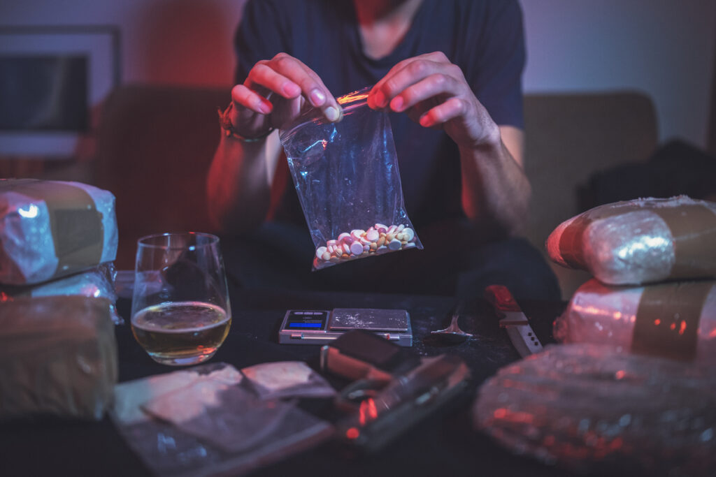 Person handling illegal stimulant pills and drug packages on a table in Spokane WA