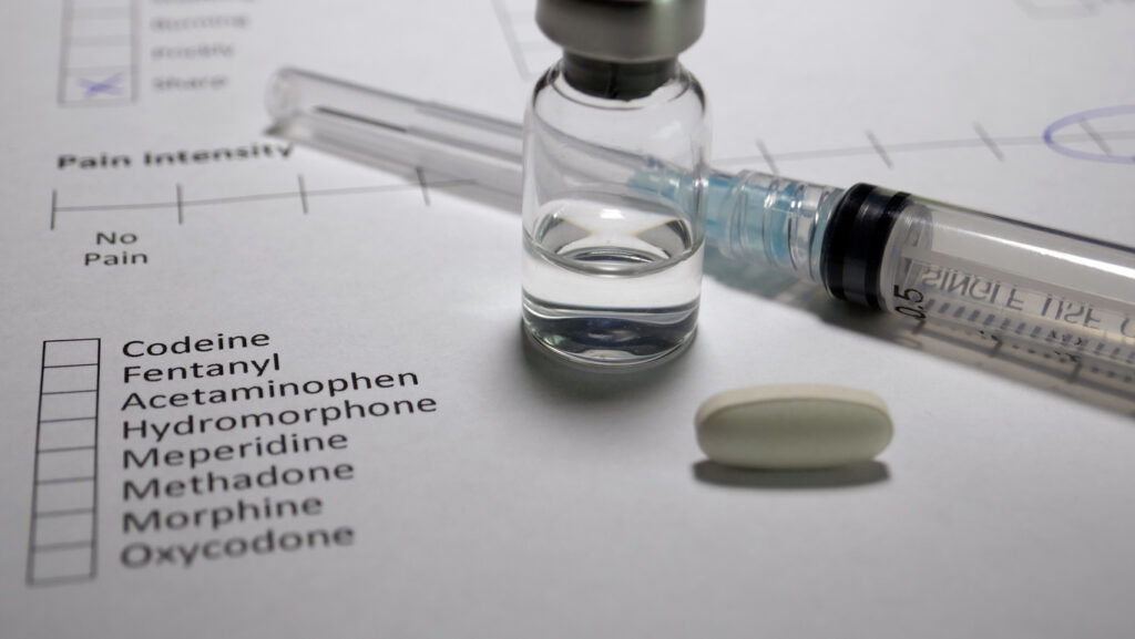 Medical syringe, pill, and prescription chart listing oxycodone and hydrocodone pain medications in Spokane WA