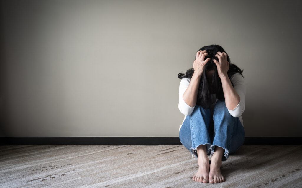 Woman sitting on the floor with her head in her hands, showing signs of stress and addiction — Spokane, WA