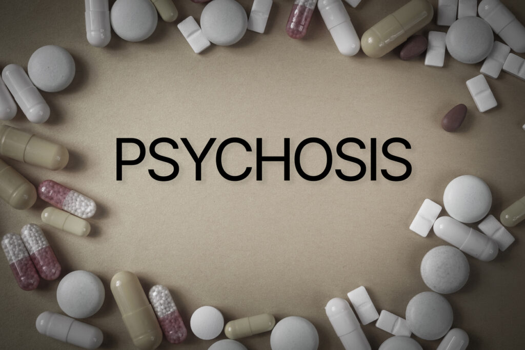 Word “psychosis” surrounded by scattered pills symbolizing amphetamine psychosis and drug abuse in Spokane WA