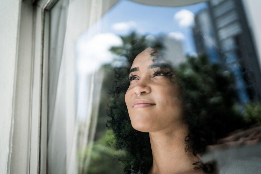 Smiling woman looking out a window, representing patience and delayed gratification in Spokane WA