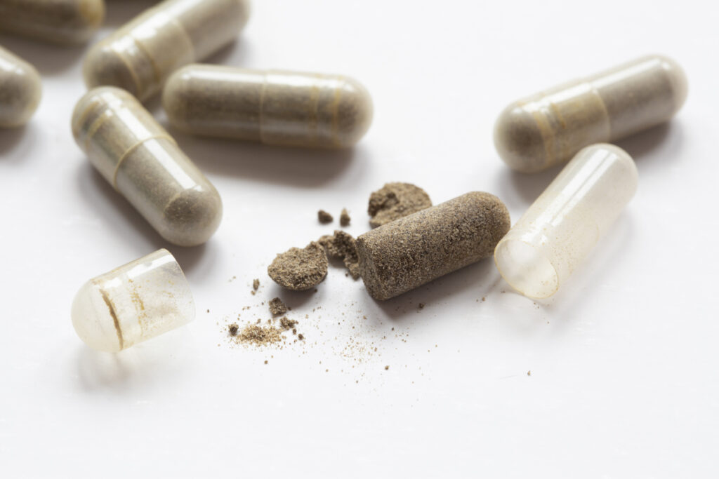 Opened kratom capsules with brown powder showing Kratom Drug Addiction effects in Spokane WA