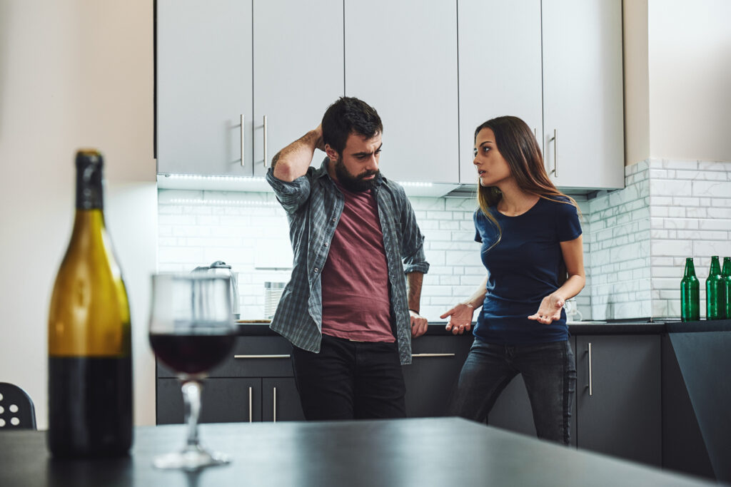 arguing couple in kitchen with wine bottle on table highlighting married to an alcoholic stressors and conflict in Spokane, WA and Spokane Valley, Washington State
