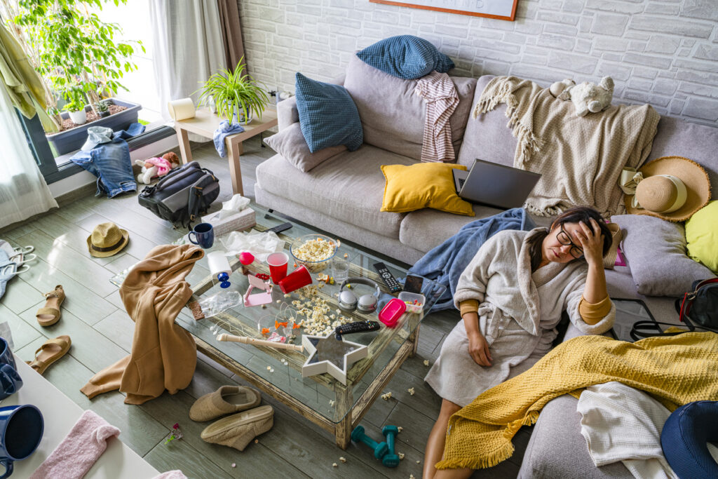 messy living room with spilled cups, cluttered table, and exhausted woman holding head — lifestyle indicators and environmental signs of drug addiction in Spokane Valley, Washington State (WA)
