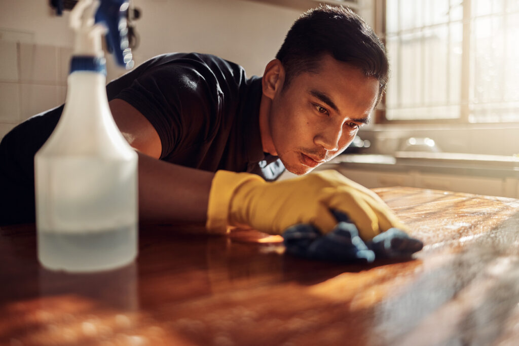 Man intensely scrubbing a kitchen counter with gloves and spray bottle, illustrating obsessive compulsive personality disorder treatment in Spokane, WA