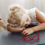 A young girl leaning her head on the table suffering from ADHD inattentive type