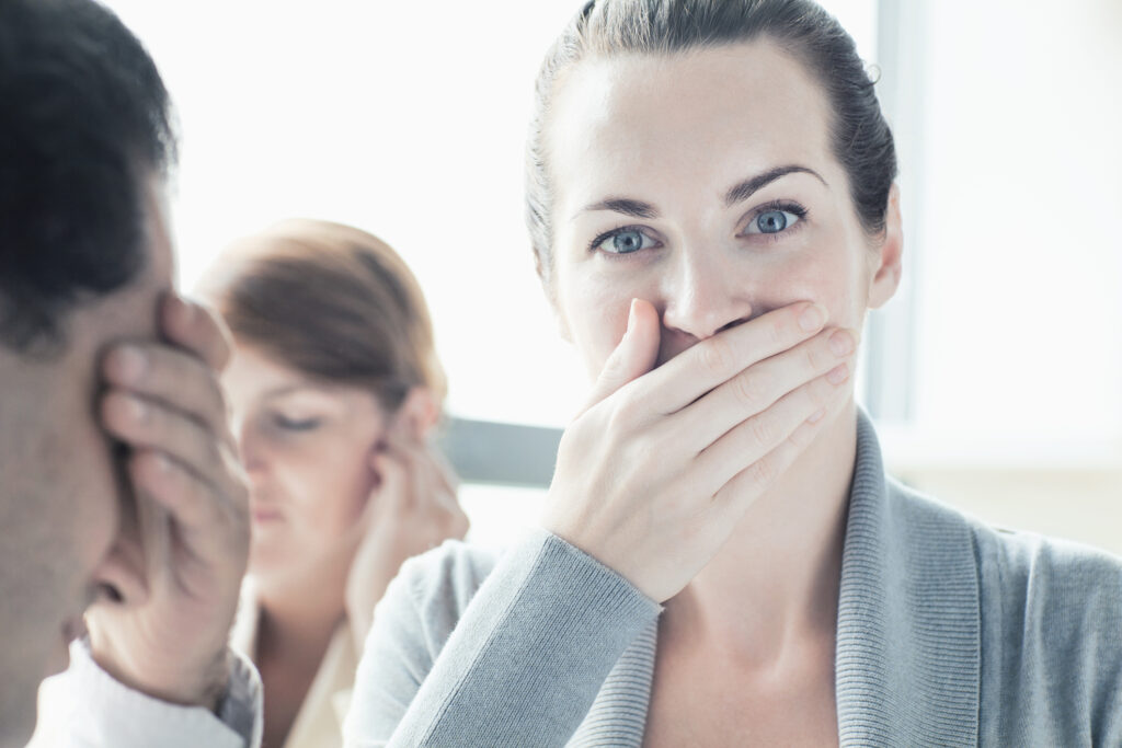 Woman covering mouth feeling queasy with stressed coworkers behind her, addressing can anxiety cause nausea in Spokane, WA