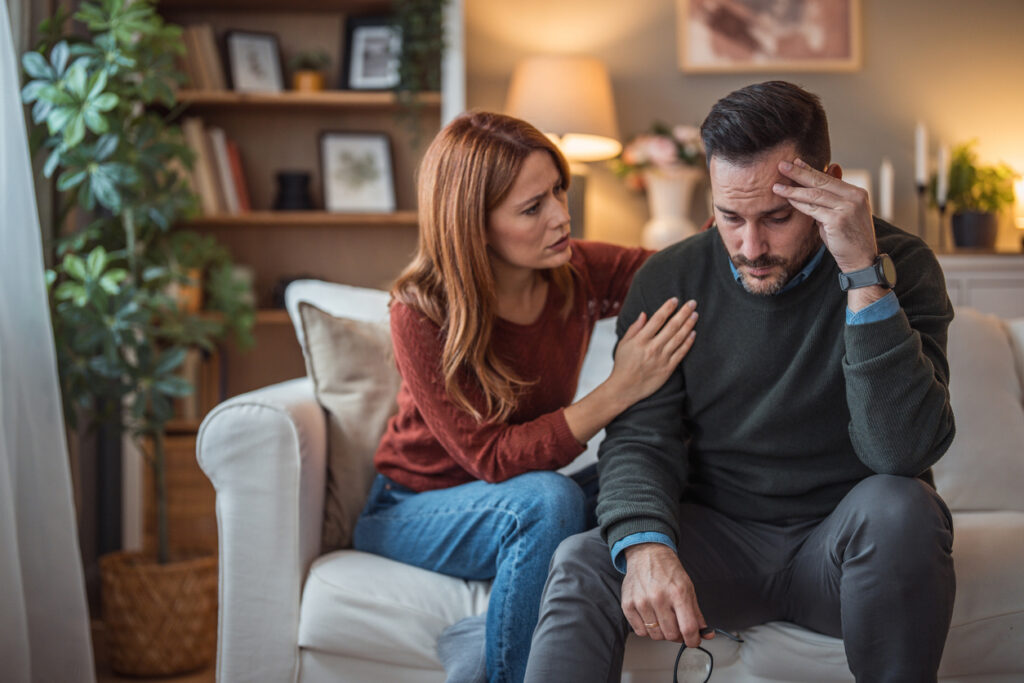 Woman comforting a depressed man on a couch — how to help someone with depression in Spokane, WA