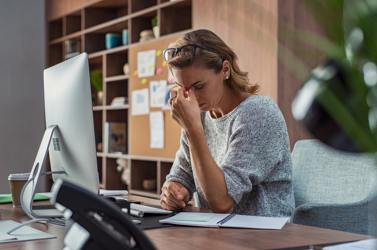 Woman rubbing her eyes at desk, signs of mild depression impacting work in Spokane Valley, WA