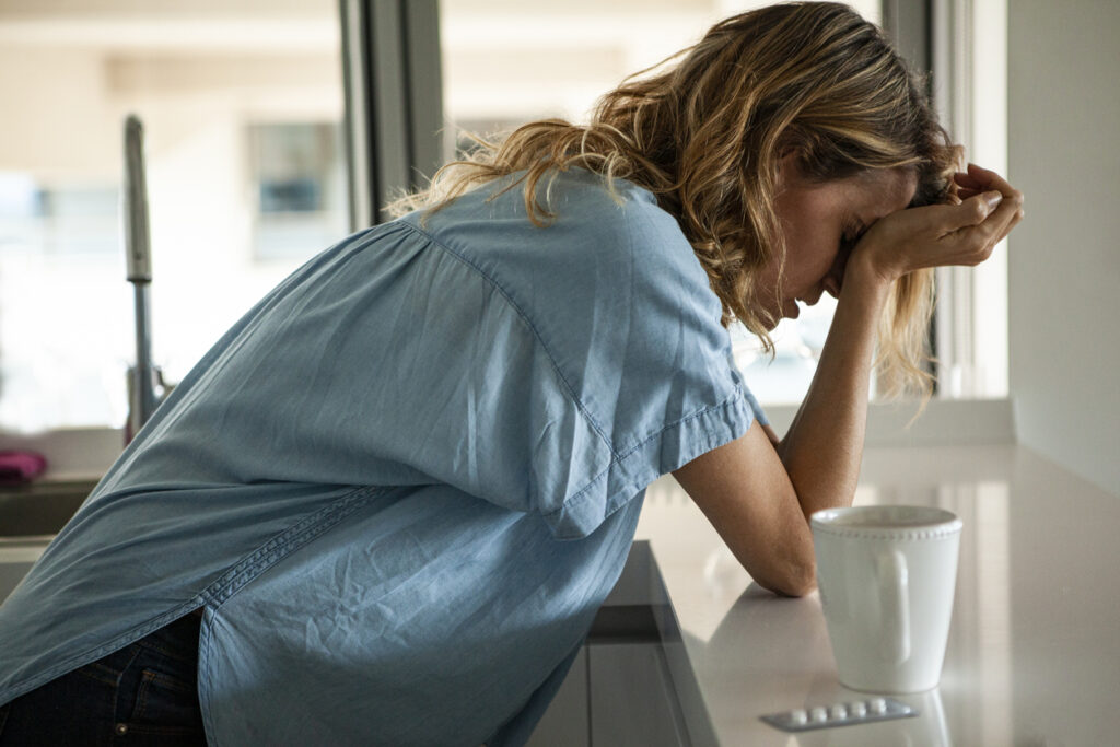 Woman leaning on kitchen counter with head in hands beside blister pack, major depressive disorder medication in Spokane, WA