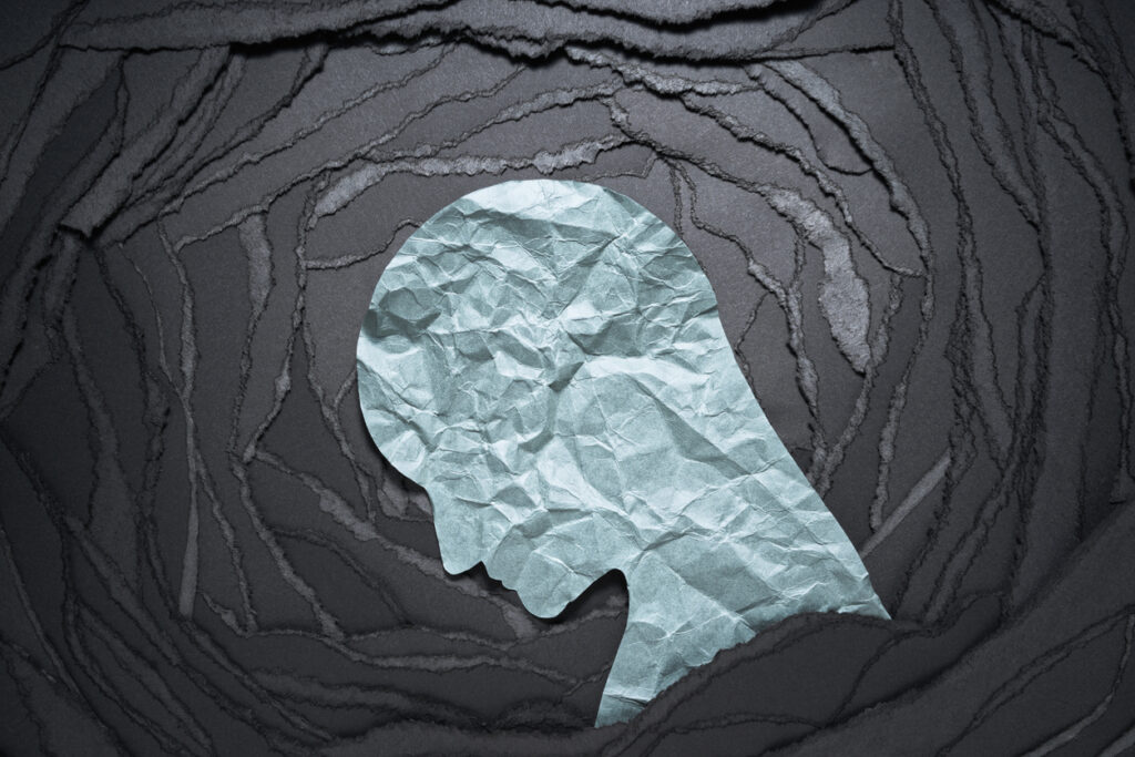 Paper silhouette of a head on dark torn background, highlighting schizophrenia suicide risk awareness in Spokane Valley, WA