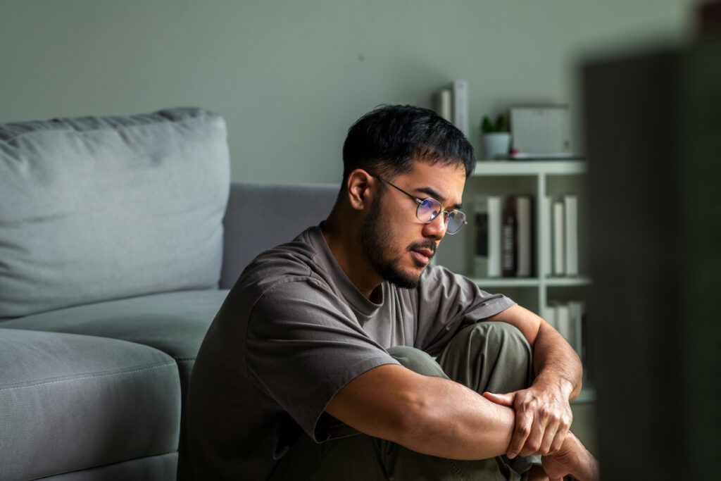 Man sitting on the floor hugging his knees, highlighting schizophrenia suicide risk awareness in Washington State