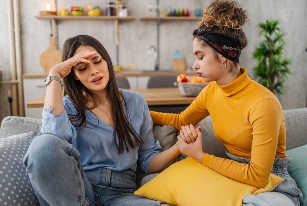 Friend comforting distressed woman on couch, showing how to help someone with borderline personality in Spokane, Washington State (WA)