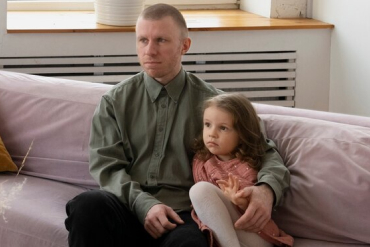 A father sitting on a couch with his daugther