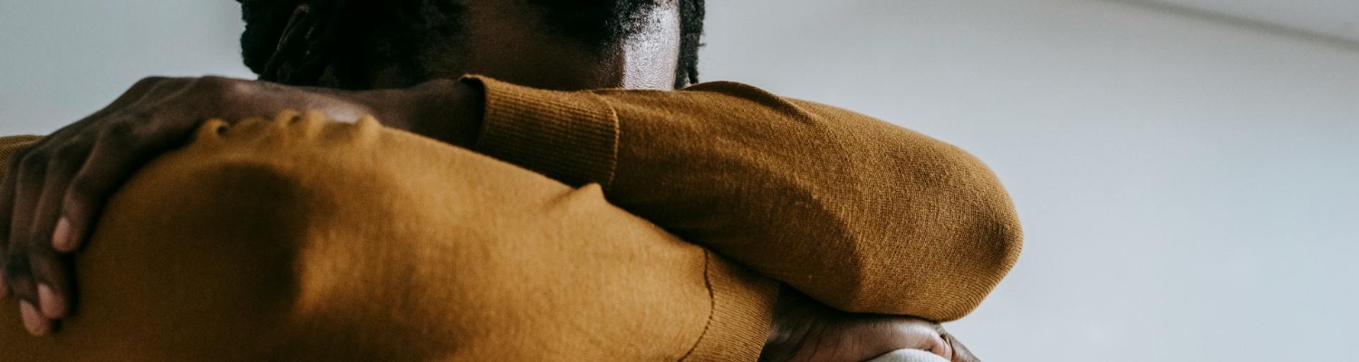 A person sitting alone and hiding their face