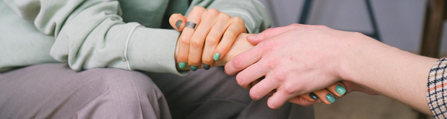 Two people holding hands in support 