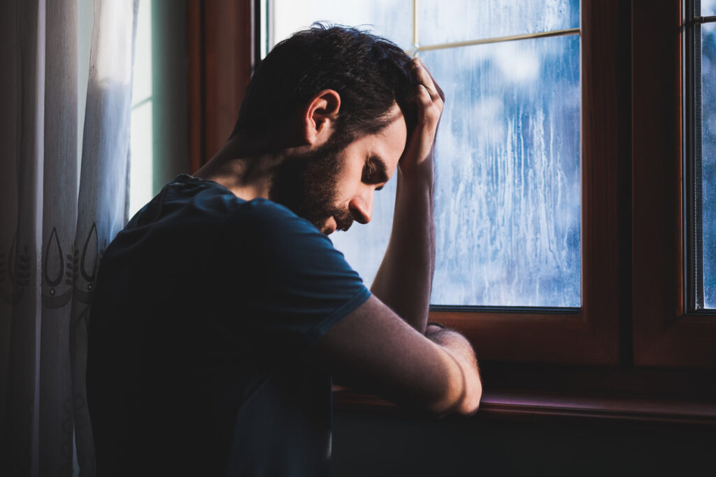 Man leaning against a cold window on a gray day — seasonal affective disorder support in Spokane, WA