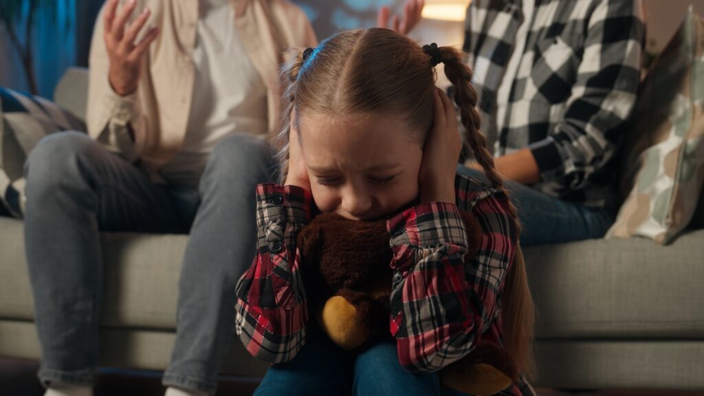 Upset child covering ears while parents argue in background BPD and childhood trauma awareness in Spokane, WA