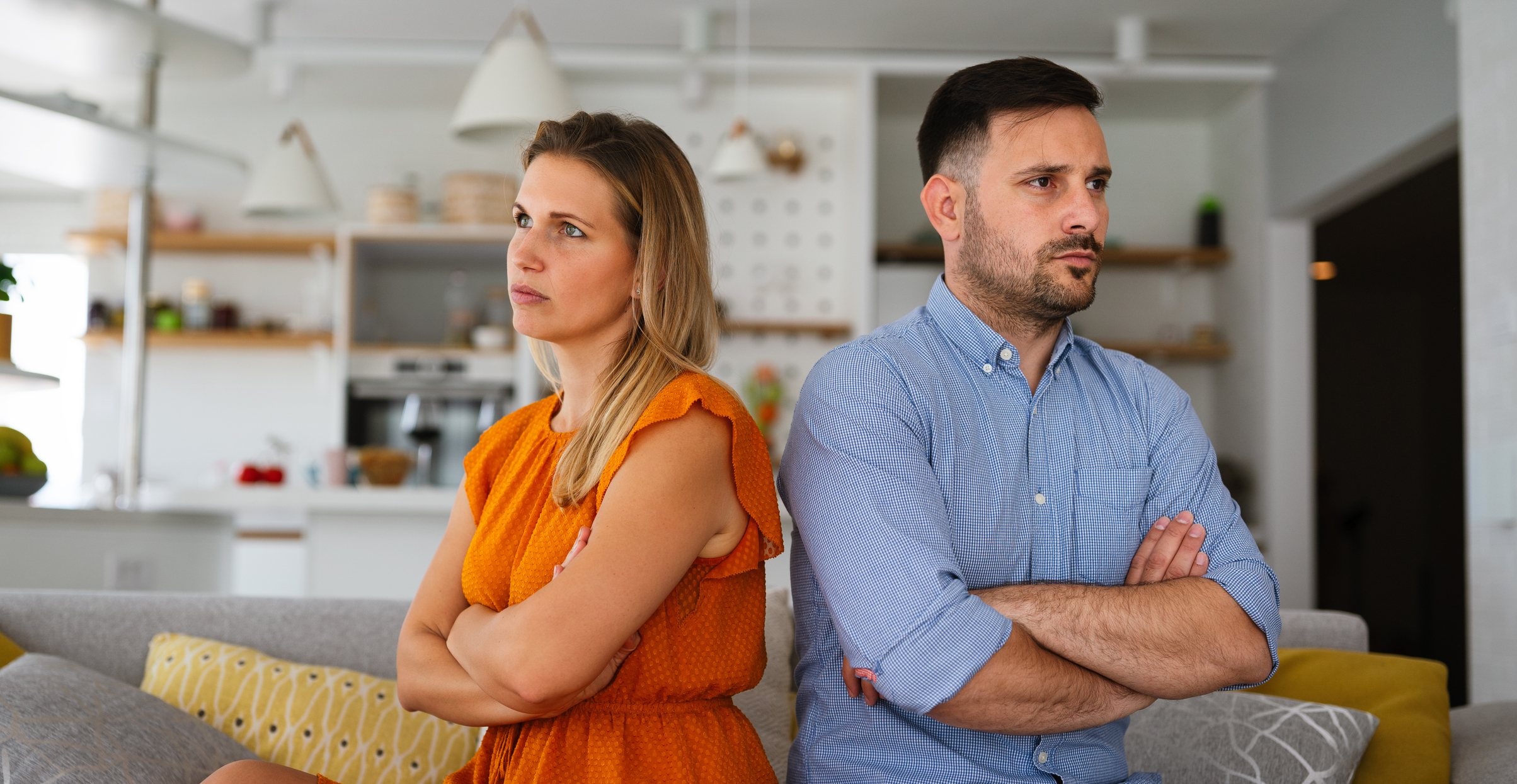 Couple sit with arms crossed and avoid eye contact, illustrating an emotionally unavailable partner in Spokane, WA
