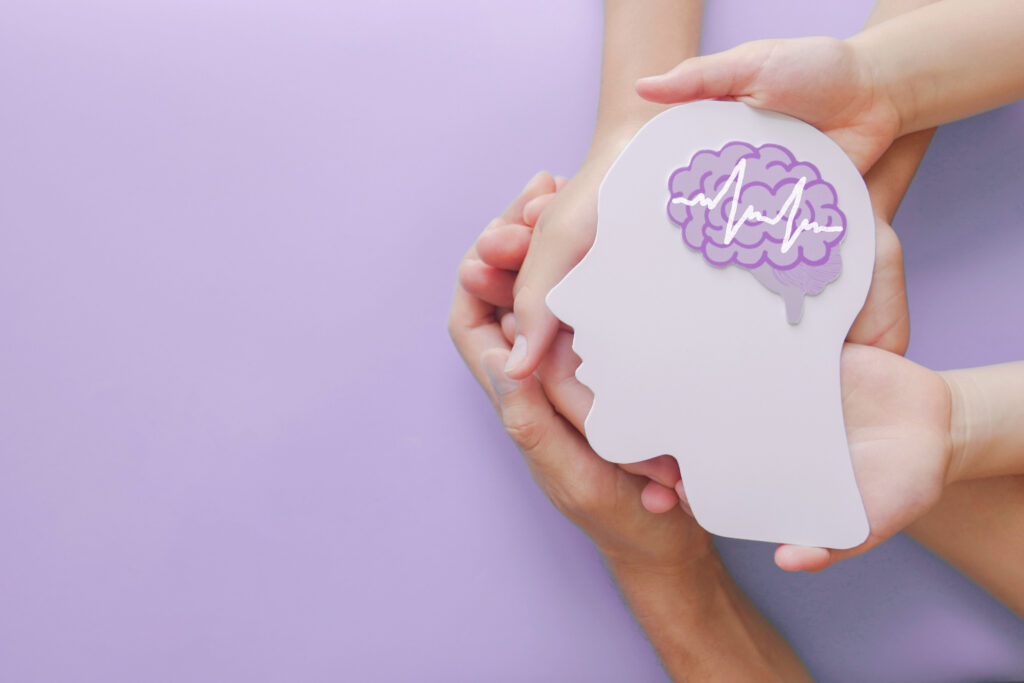 Hands holding a paper cutout of a human head with a brain illustration, symbolizing ADHD medication and mental health treatment in Spokane Valley, Washington.