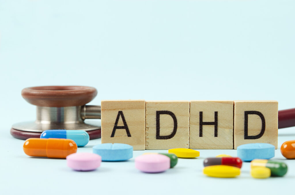 ADHD medication pills and a stethoscope on a blue background, representing medical treatment for attention deficit hyperactivity disorder in Spokane Valley, Washington.