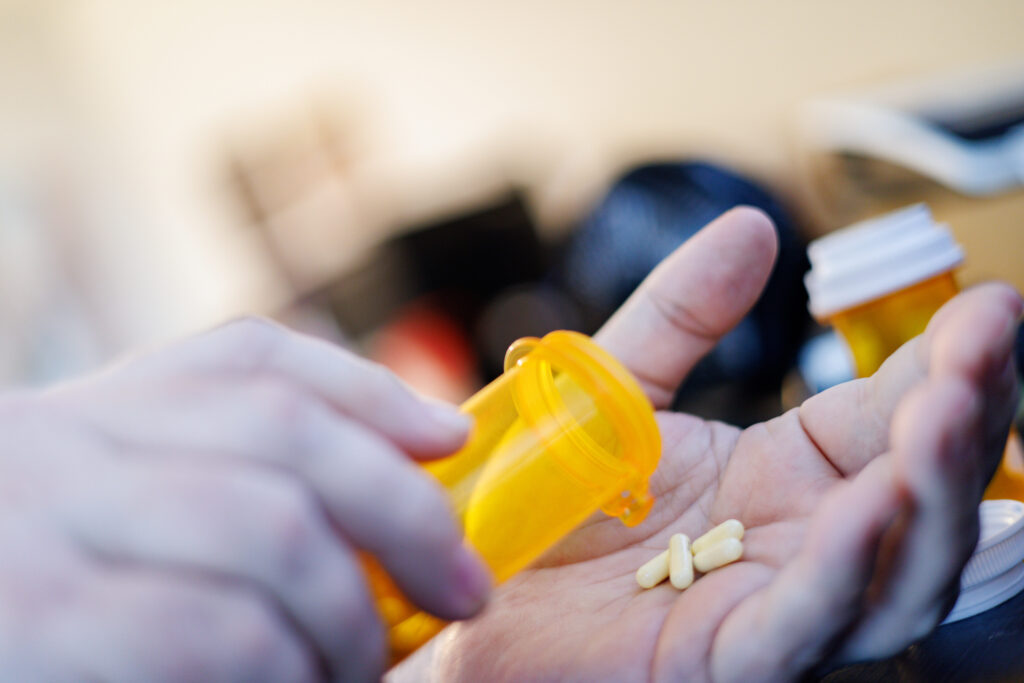 Close-up of a person pouring ADHD medication capsules from a prescription bottle into their hand in Spokane Valley, Washington, representing responsible treatment and medication management.