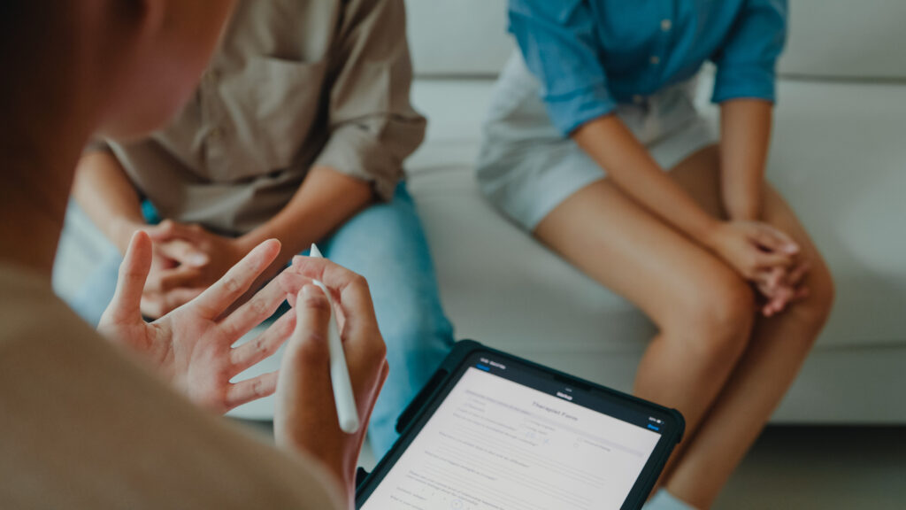 Couple attending a therapy session with a counselor taking notes on a tablet in Spokane Valley WA discussing divorce and mental health support