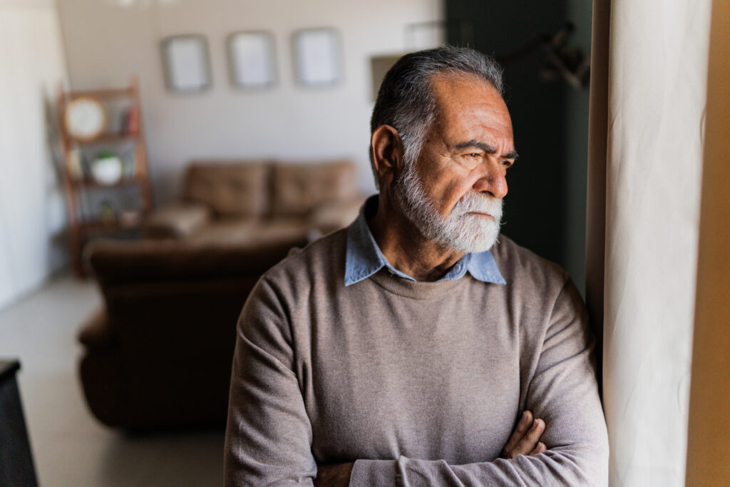 Older man looking out the window with a thoughtful expression, symbolizing depression screening for seniors using the Geriatric Depression Scale in Spokane, Washington.
